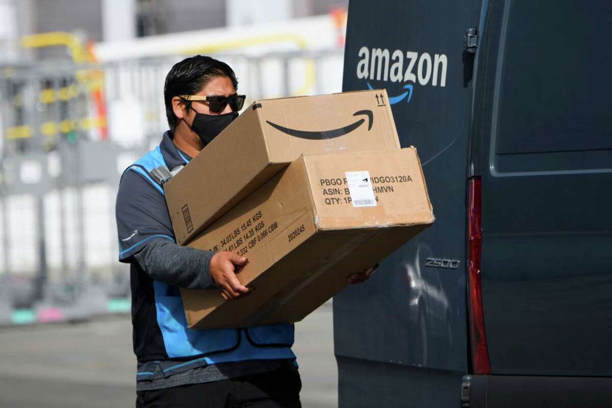 An Amazon.com Inc. delivery driver carries boxes into a van outside of a distribution facility in Hawthorne (Los Angeles County) in February. On Monday, the state announced an agreement with Amazon to overhaul how the company notifies its tens of thousands of employees statewide about COVID-19 infections.