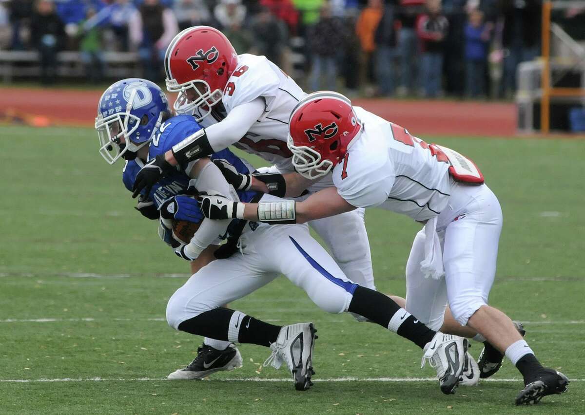 New Canaan's Cameron Armstrong (36) and Willie Gould (7) bring down Darien's Graham Maybell (22) during the Turkey Bowl football game between New Canaan and Darien in Darien on Nov. 25, 2010.
