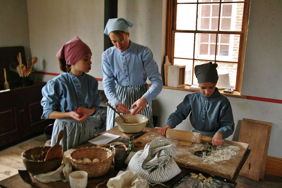People dressed in traditional Swedish attire bake cookies at the Bjorklund Hotel in Bishop Hill. Cooking baking will be featured during Bishop Hill's upcoming Julmarknad, or Christmas market.