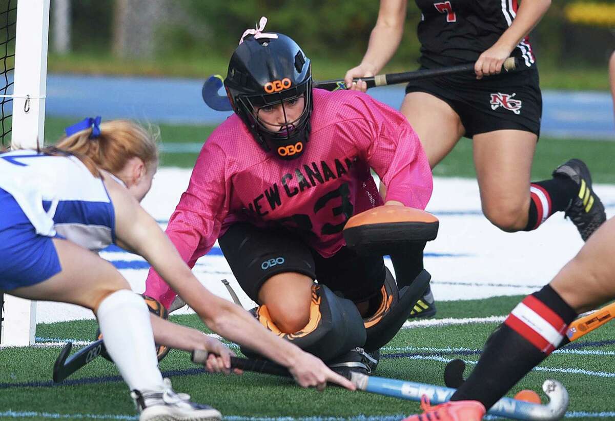 New Canaan goalie Grace Gilman dives out to play the ball during the Rams’ field hockey game in Darien in October.