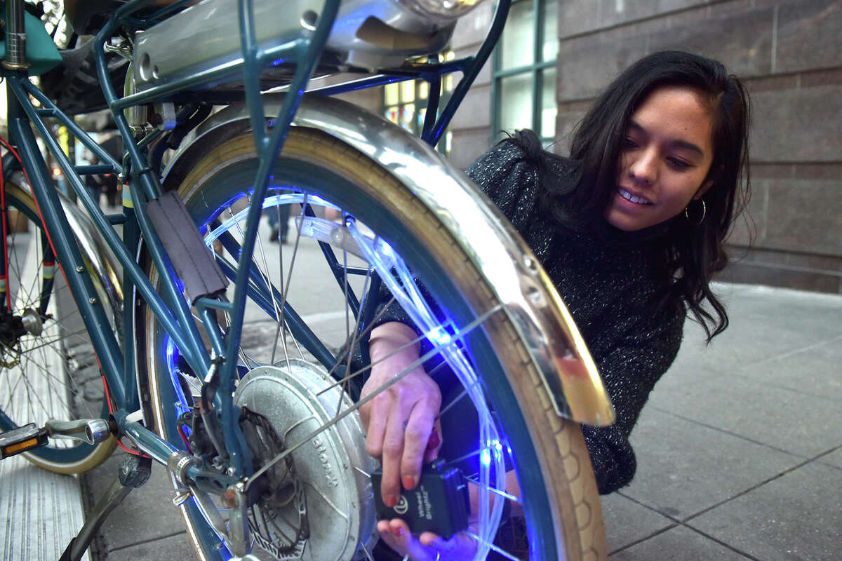 Alicia Tapia weaves blue string lights into the wheels of Bibliobicicleta, a mobile bike library, at Safe Passage Park in the Tenderloin. 