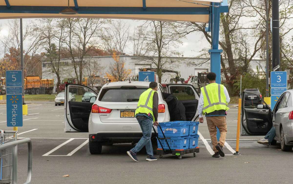 Walmart employees are seen bringing groceries to a customer in an outside pickup area in the parking lot of Walmart on Washington Ave. Ext. on Tuesday, Nov. 16, 2021 in Albany, N.Y. Walmart is among the large and small retailers ramping up hiring efforts for the coming holiday season.
