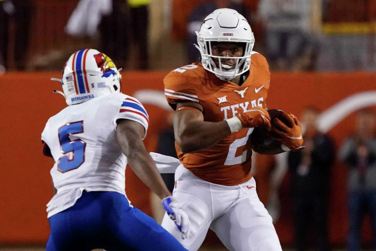 Texas running back Roschon Johnson (2) runs against Kansas safety O.J. Burroughs (5) during the second half of an NCAA college football game in Austin, Texas, Saturday, Nov. 13, 2021.