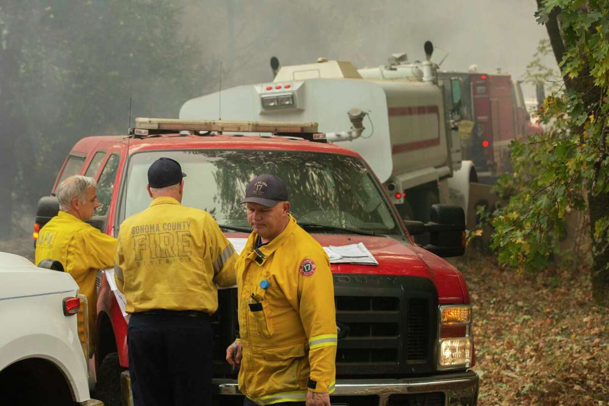 Napa and Sonoma County fire officials look over maps along Spring Mountain Road in St. Helena after a private firefighter crew allegedly lost control of an unauthorized backfire that spread in an area near them in October 2020.