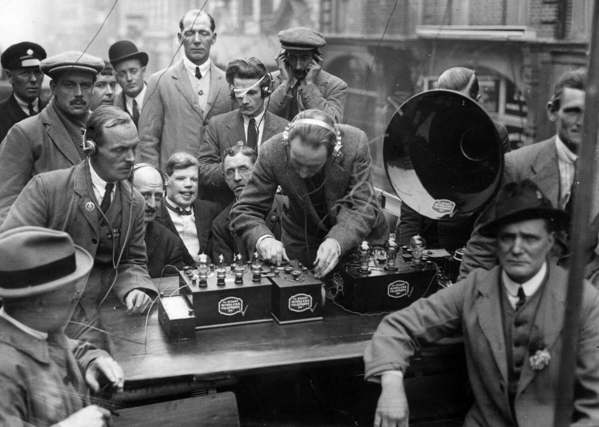 1921: Christmas takes the radio Many of today’s traditions began during Prohibition-era America. With the ubiquity of the radio by this time, the recent invention had become the most popular gift and also the center of most social gatherings—particularly for live-broadcasted holiday concerts. [Pictured: Radio enthusiasts in 1922 receiving concert broadcasts on a radio apparatus and relaying them through a loudspeaker and headphones.]