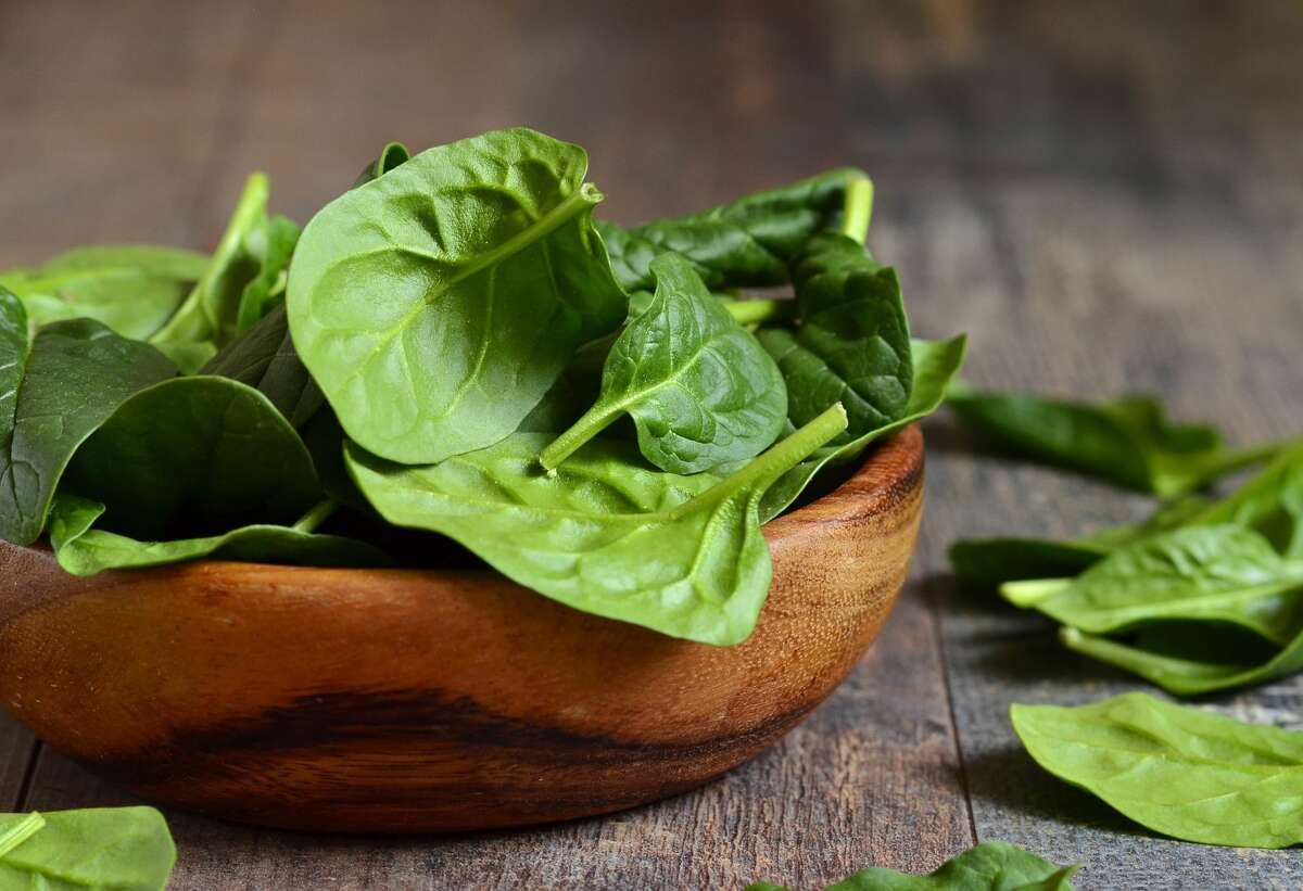 A file image of Spinach leaves in a wooden bowl.