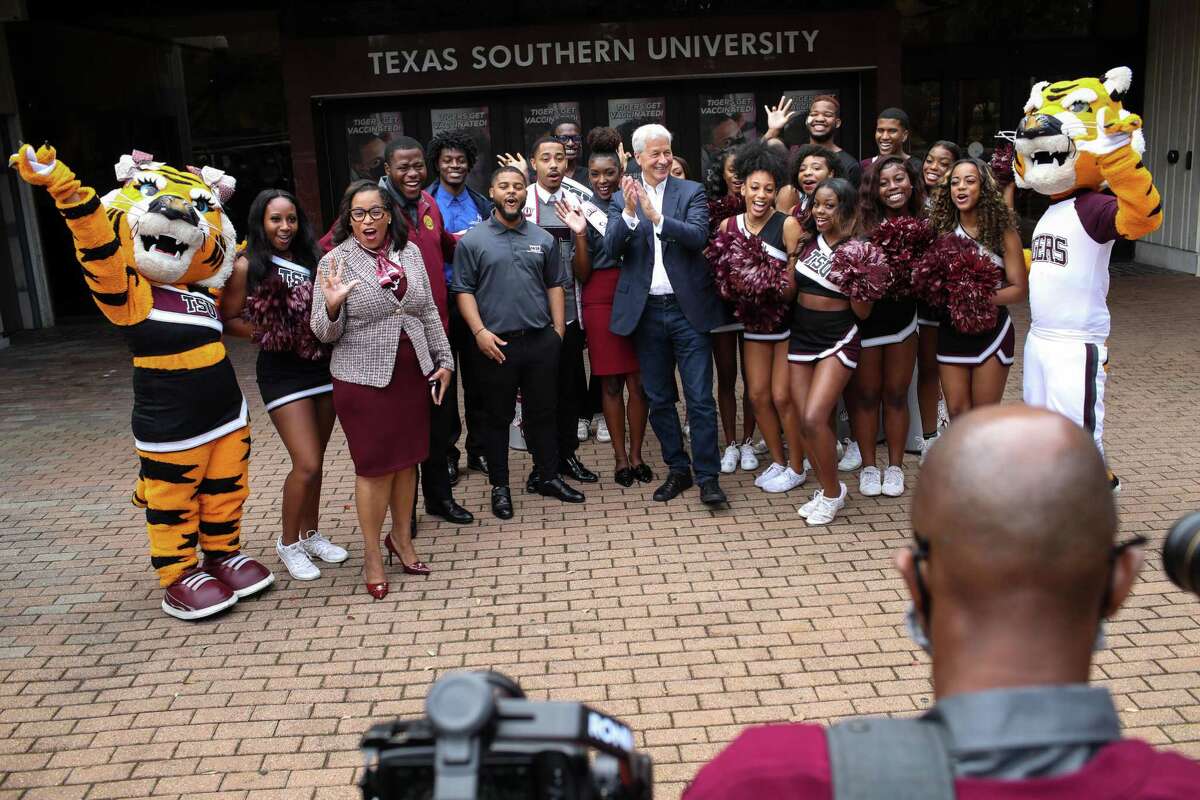 Jamie Dimon, CEO of JPMorgan Chase, center, and Texas Southern University President Lesia Crumpton-Young, third from left, pose for a photo with cheerleaders and student leaders as they walk through campus Wednesday, Oct. 27, 2021, at Texas Southern University in Houston.