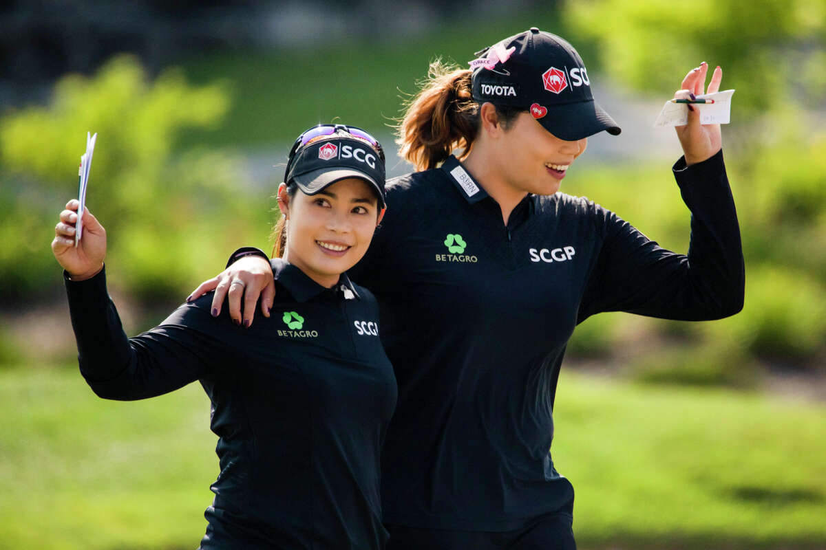 LPGA players Moriya Jutanugarn, left, and Ariya Jutanugarn, right, wave to the crowd after securing their victory in the Dow Great Lakes Bay Invitational Saturday, July 17, 2021 at the Midland Country Club. (Drew Travis/for the Daily News)
