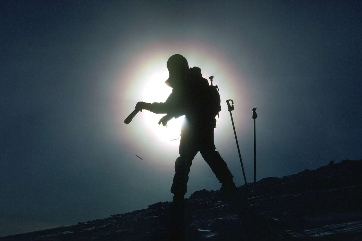 A silhouette of a ski patroller throwing dynamite to release avalanches and keep the ski resort safe for the public.