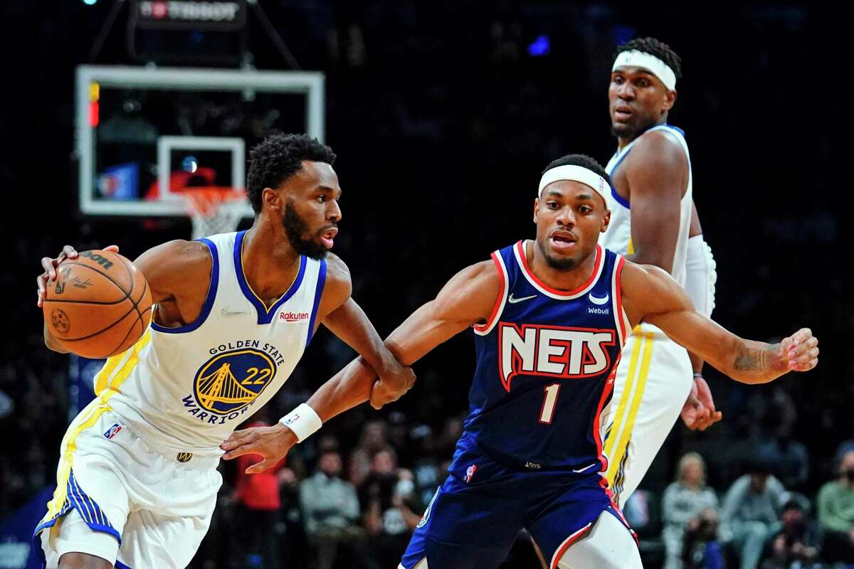 Golden State Warriors' Andrew Wiggins (22) drives past Brooklyn Nets' Bruce Brown (1) during the first half of an NBA basketball game Tuesday, Nov. 16, 2021 in New York. (AP Photo/Frank Franklin II)