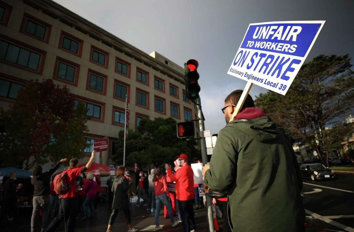 SAN FRANCISCO, CALIFORNIA - NOVEMBER 10: A union worker holds a strike sign as he pickets with nurses outside of the Kaiser Permanente San Francisco Medical Center on November 10, 2021 in San Francisco, California. (Photo by Justin Sullivan/Getty Images)