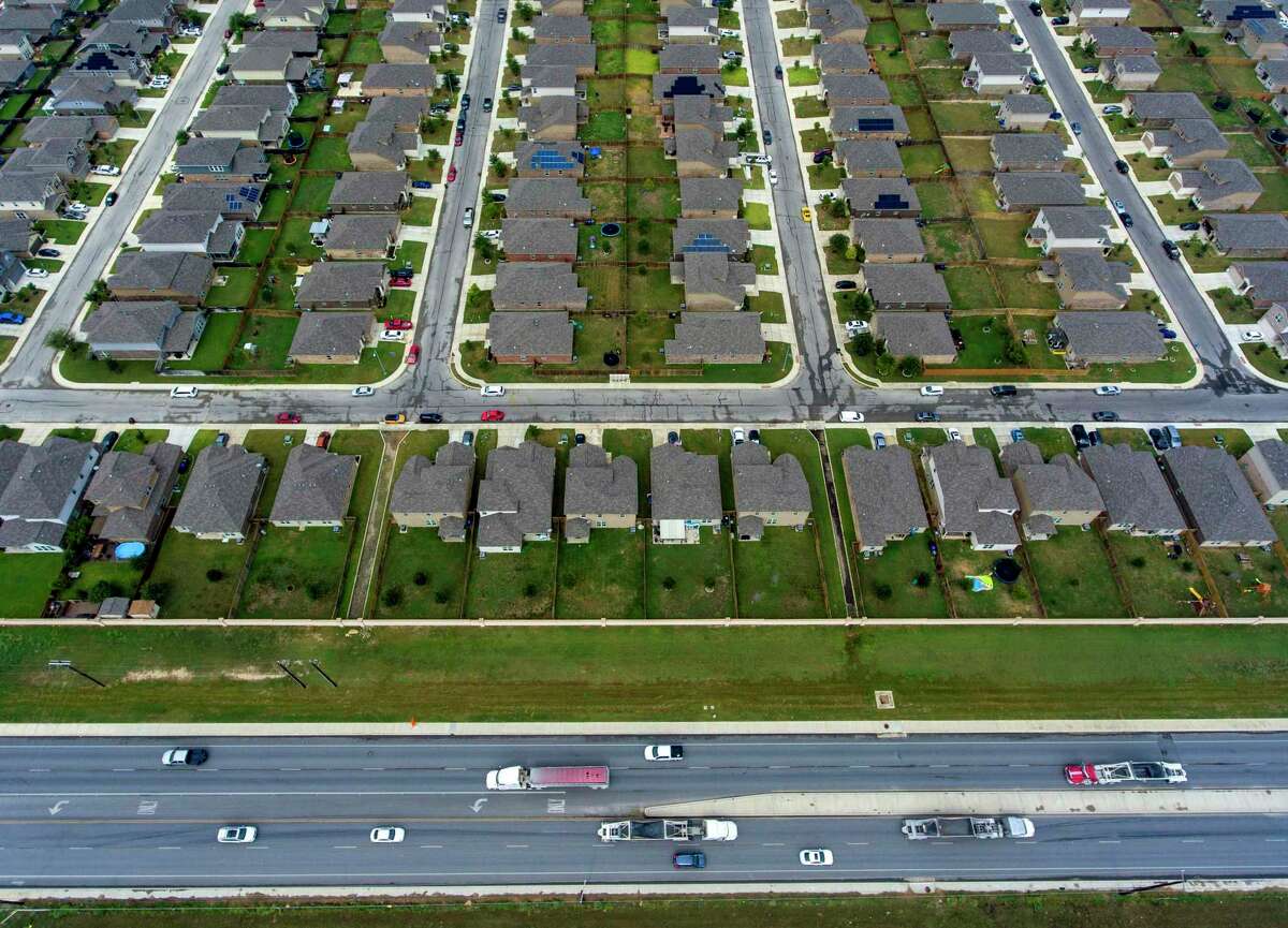 A subdivision of homes seems to dwarf cars and trucks driving on Culebra Road outside Loop 1604.