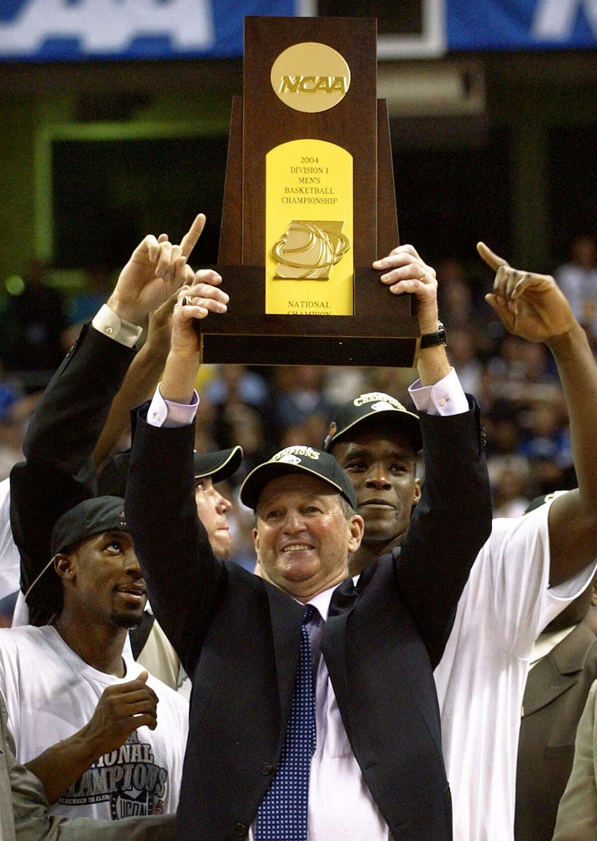 UConn men’s basketball coach Jim Calhoun raises the trophy after beating Georgia Tech to win the 2004 national championship. Calhoun, who built UConn into a national power by winning three national championships, retired from coaching on Thursday.