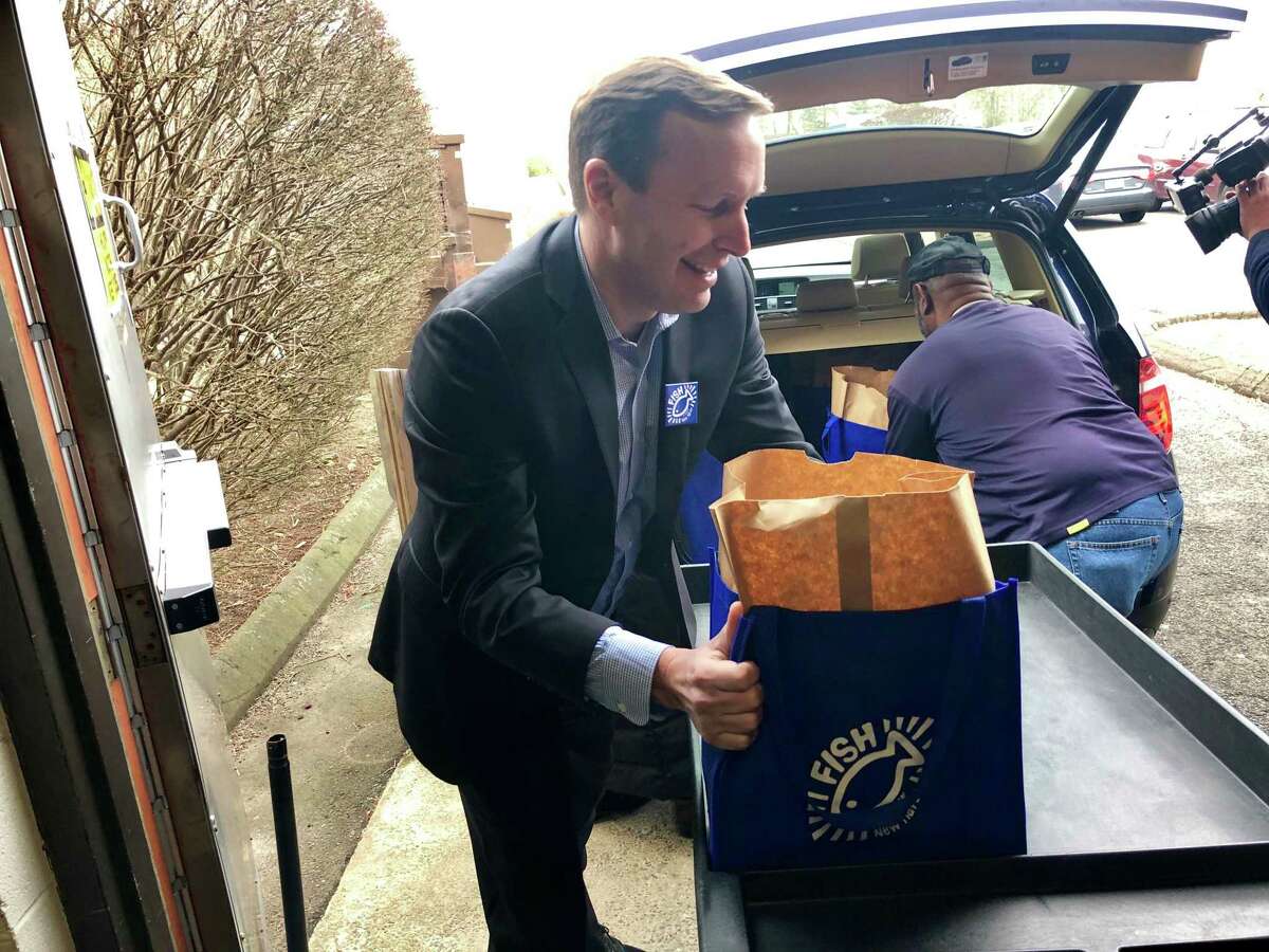 U.S. Sen. Chris Murphy assists with grocery deliveries at FISH of Greater New Haven on Friday, Dec. 14, 2018.