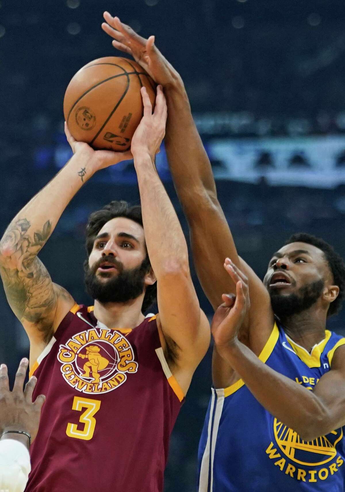 Golden State Warriors' Andrew Wiggins (22) knocks the ball loose from Cleveland Cavaliers' Ricky Rubio (3) as Kevon Looney (5) watches in the first half of an NBA basketball game, Thursday, Nov. 18, 2021, in Cleveland. (AP Photo/Tony Dejak)