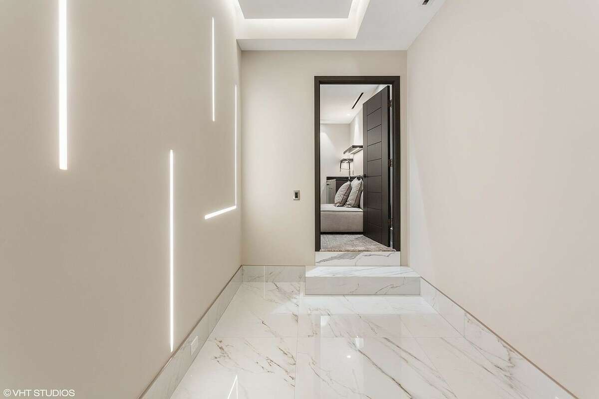 Hallway with marble floors and wall lighting.