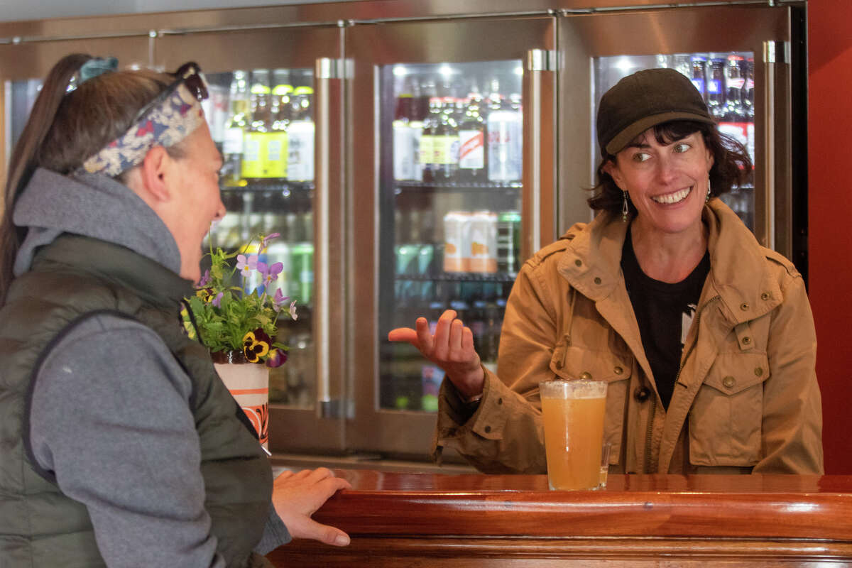 Leila Monroe (right), the owner of Smiley's Saloon, talks with a customer at the bar.
