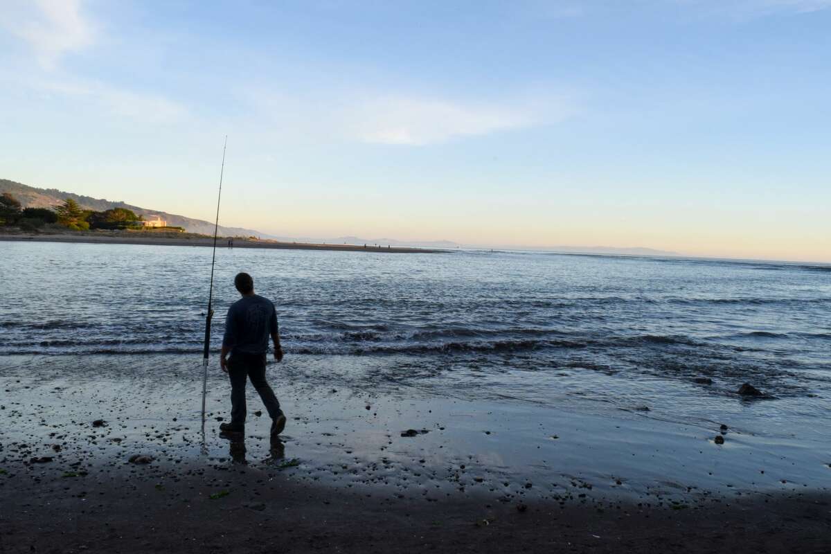 A man fishes along the shoreline in Bolinas, California.