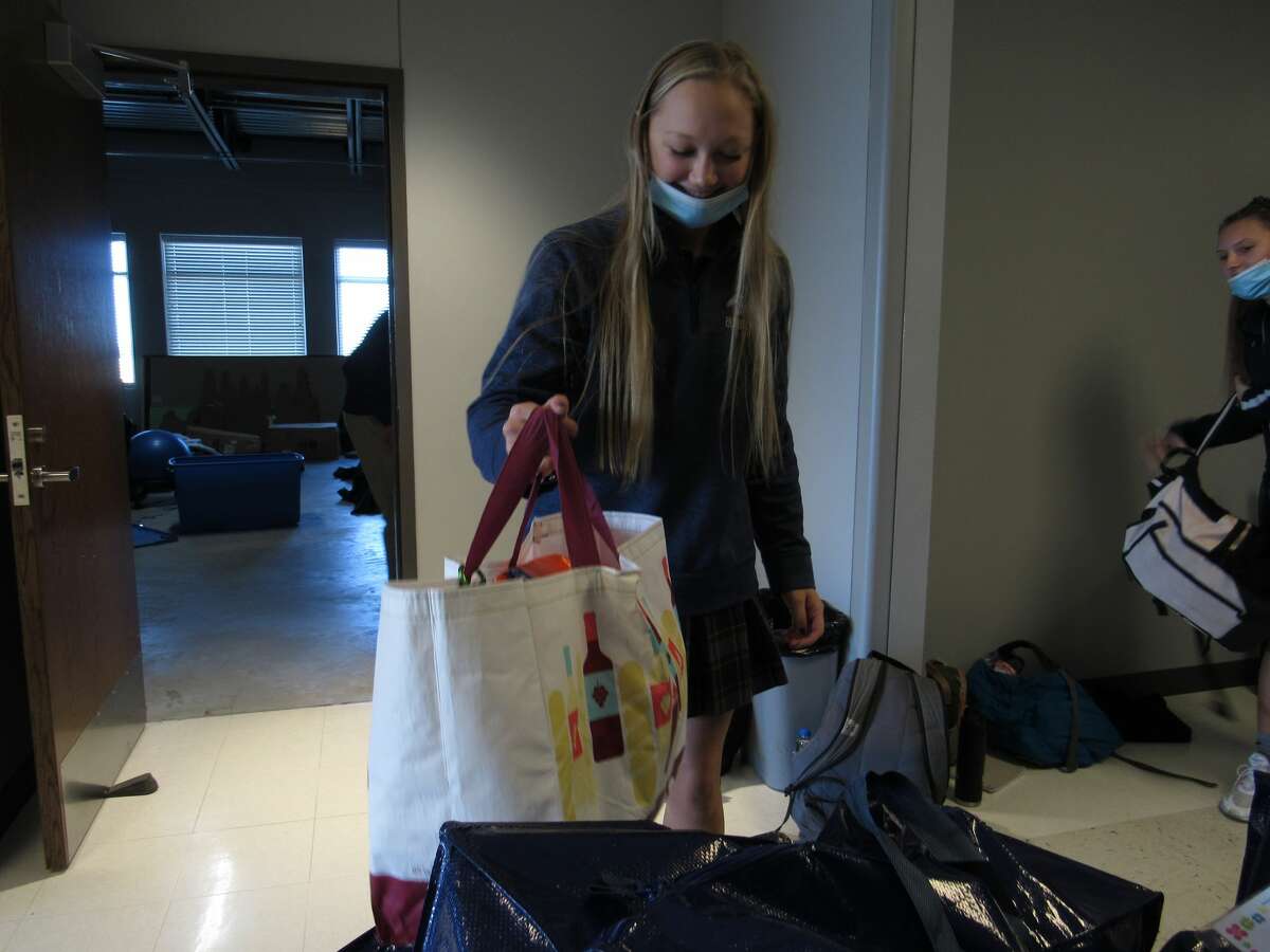 CansGiving chairperson Anne Schilly loads a bag of donated food items at Father McGivney Catholic High School on Friday. 