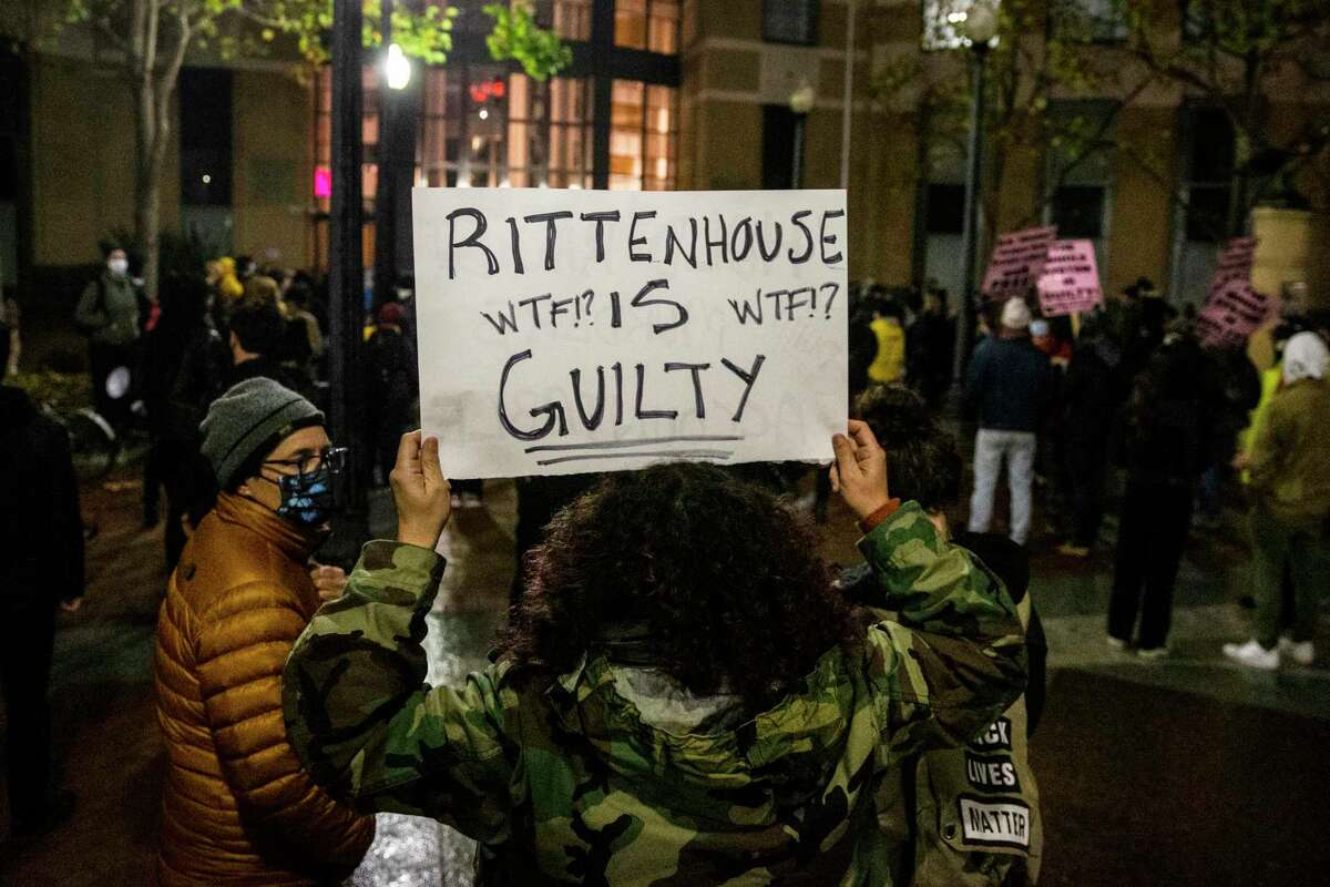 A demonstrator holds a sign during a protest against the acquittal of Kyle Rittenhouse and his role in the deadly Kenosha shooting in Oakland, Calif. Friday, Nov. 19, 2021.