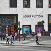 成群结队的购物者穿过旧金山高档联合广场购物区路易威登商店前的街道