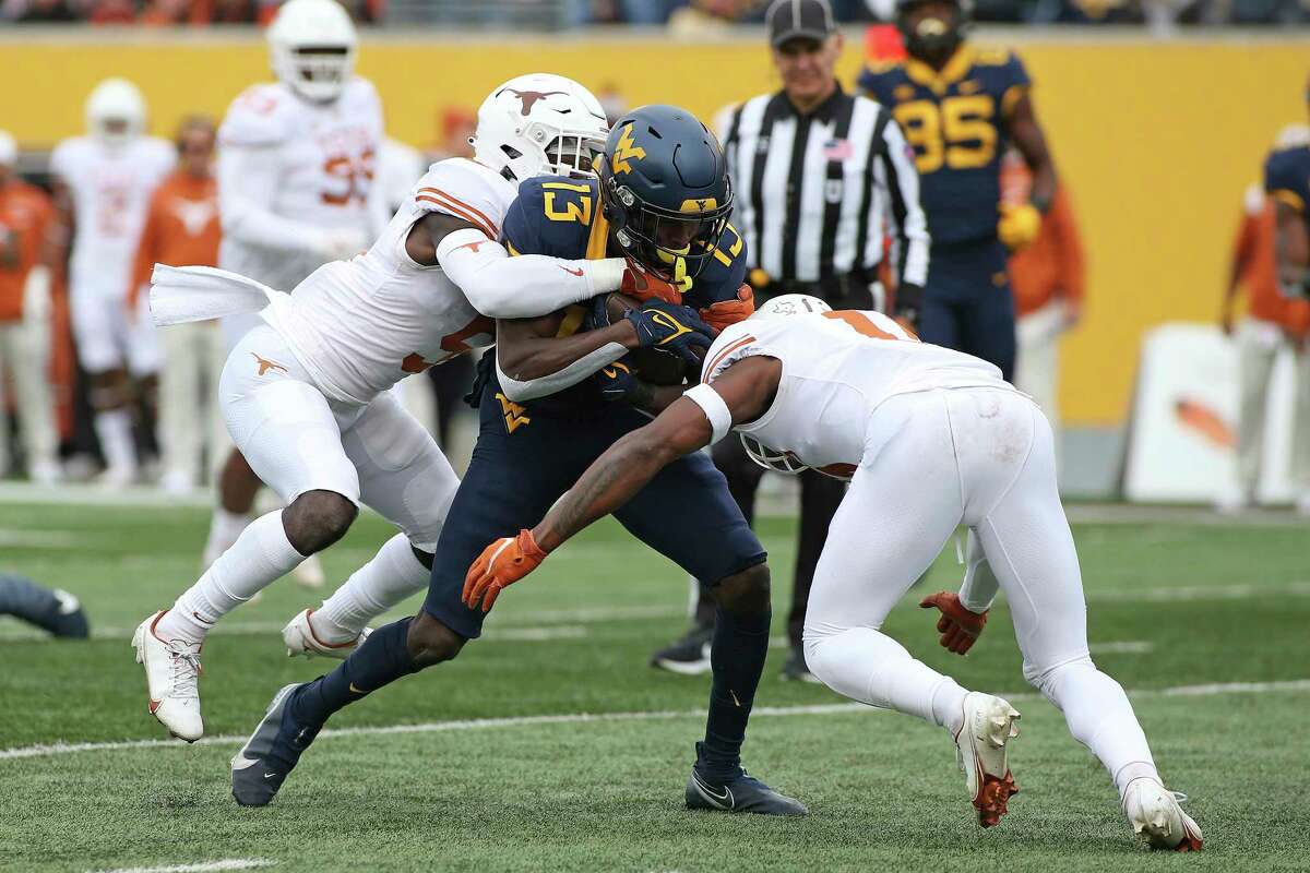 West Virginia wide receiver Sam James (13) is tackled by Texas defensive backs D'Shawn Jamison (5) and Anthony Cook (11) during the first half of an NCAA college football game in Morgantown, W.Va., Saturday, Nov. 20, 2021. (AP Photo/Kathleen Batten)
