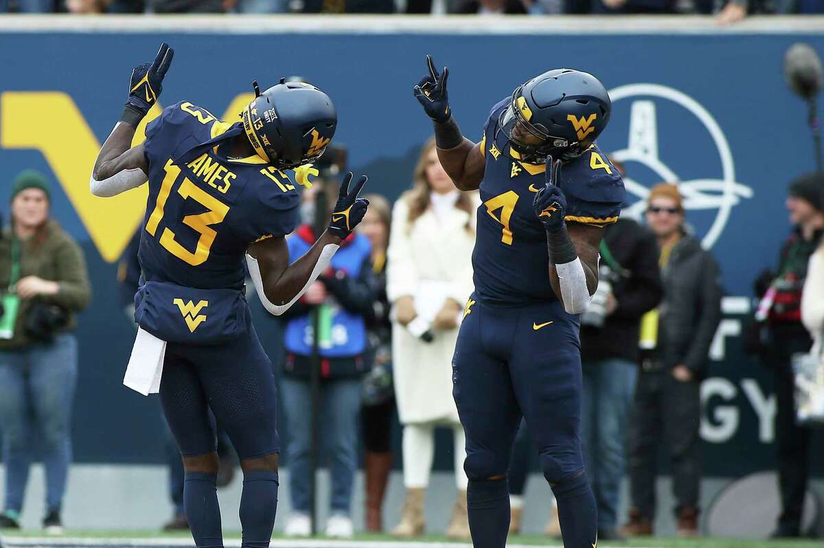 West Virginia wide receiver Sam James (13) and running back Leddie Brown (4) celebrate after James scores a touchdown against Texas during the first half of an NCAA college football game in Morgantown, W.Va., Saturday, Nov. 20, 2021. (AP Photo/Kathleen Batten)