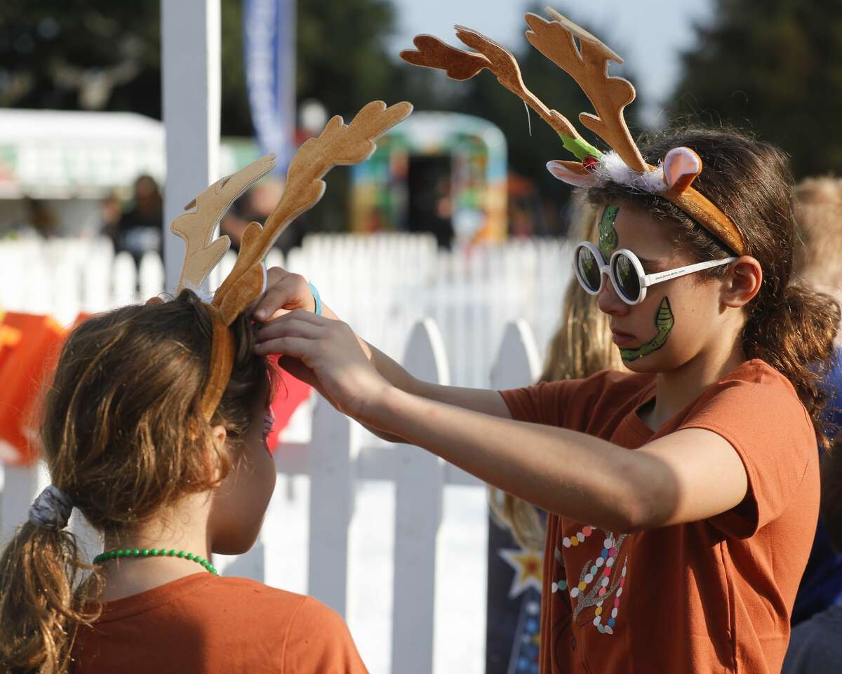 Patty Chernov helps her sister, Cora, with her reindeer headwear during the Lighting of the Doves at Town Green Park, Saturday, Nov. 20, 2021, in The Woodlands.