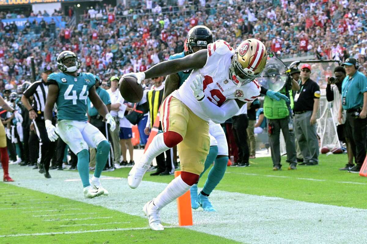 San Francisco 49ers wide receiver Deebo Samuel, right, scores a touchdown on a 25-yard run in front of Jacksonville Jaguars safety Rayshawn Jenkins, center, and linebacker Myles Jack (44) during the first half of an NFL football game, Sunday, Nov. 21, 2021, in Jacksonville, Fla. (AP Photo/Phelan M. Ebenhack)