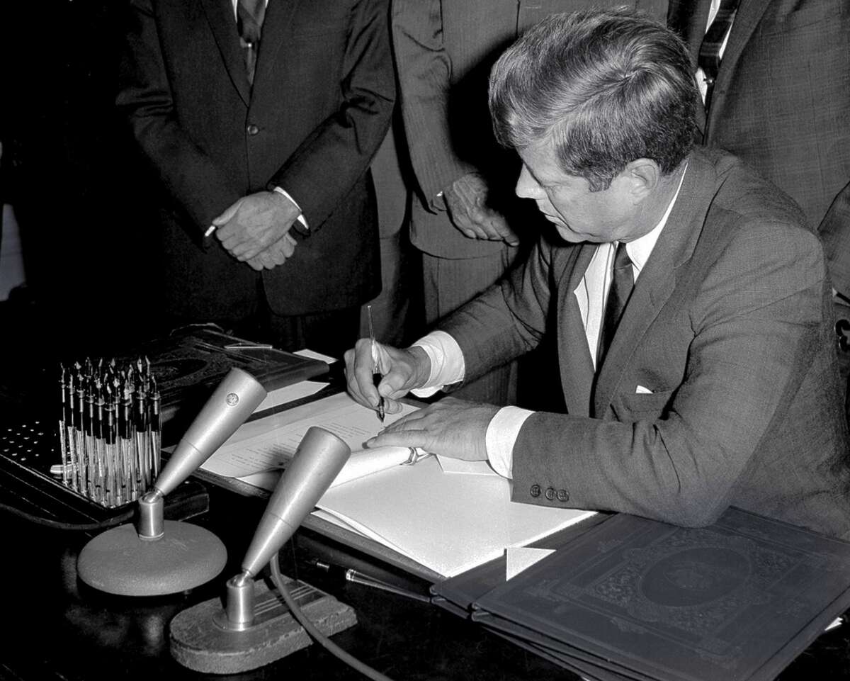 In this Oct. 7, 1963 file photo, President John F. Kennedy signs the Limited Test Ban Treaty during a ratification ceremony in the White House Treaty Room in Washington. (AP Photo/File)
