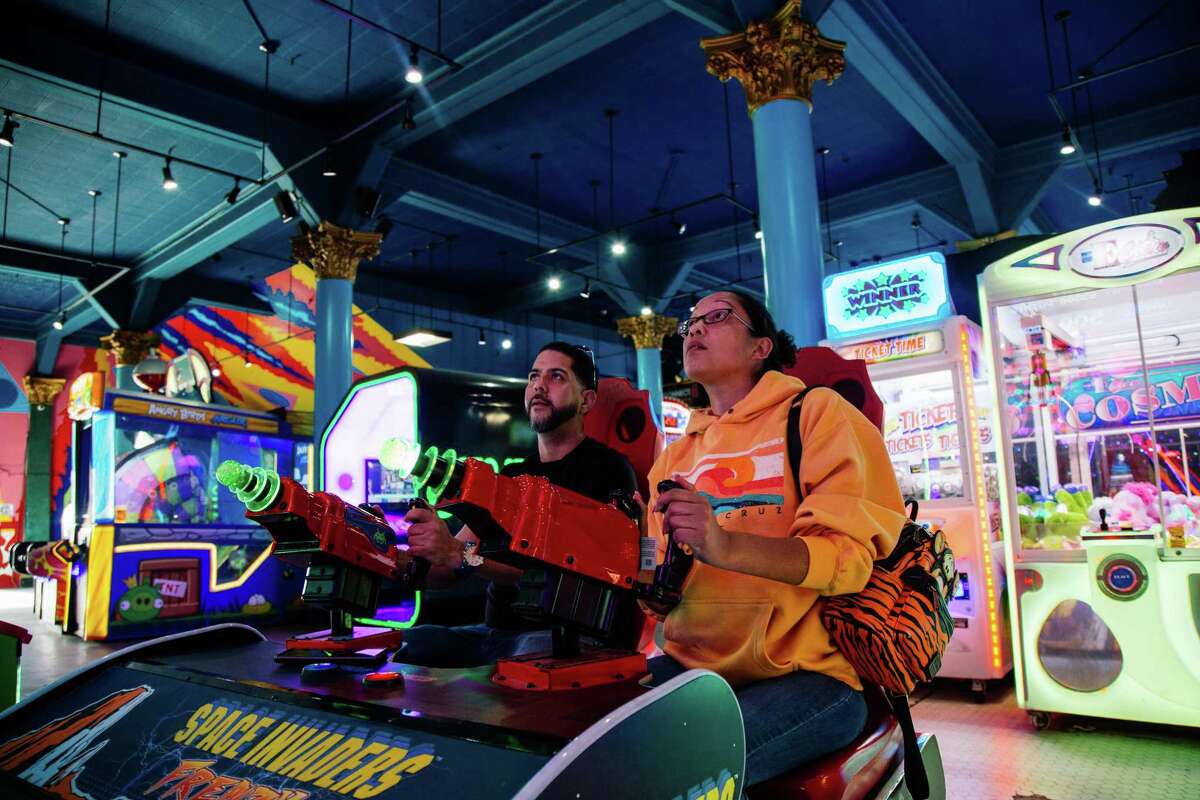 Victor Negron and Teresa Jennings play a shooting game at the Santa Cruz Boardwalk arcade on Oct. 5. Santa Cruz County became the first county in the Greater Bay Area to drop its indoor mask mandate in late September, but is reinstating the rule as COVID cases rise.