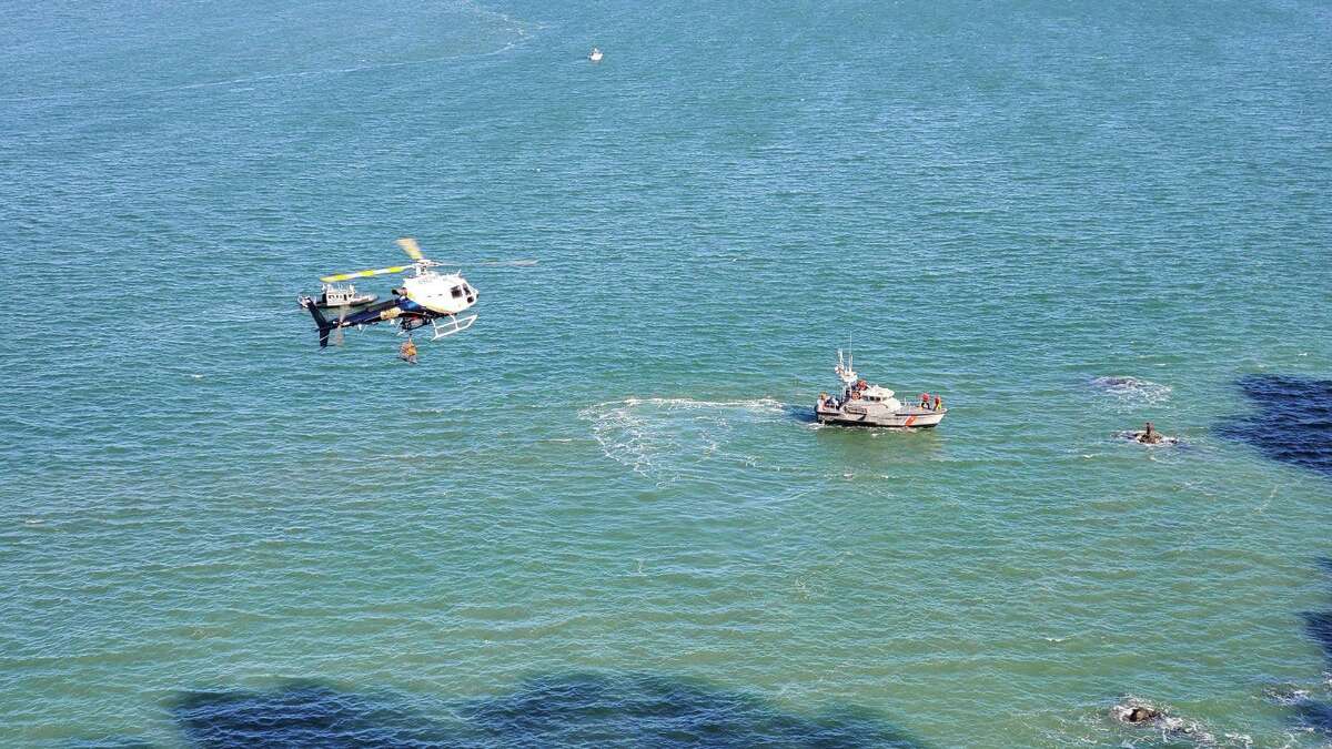 A U.S. Coast Guard boat and CHP helicopter crews rescue two people from the water off Lands End near the Golden Gate Bridge.