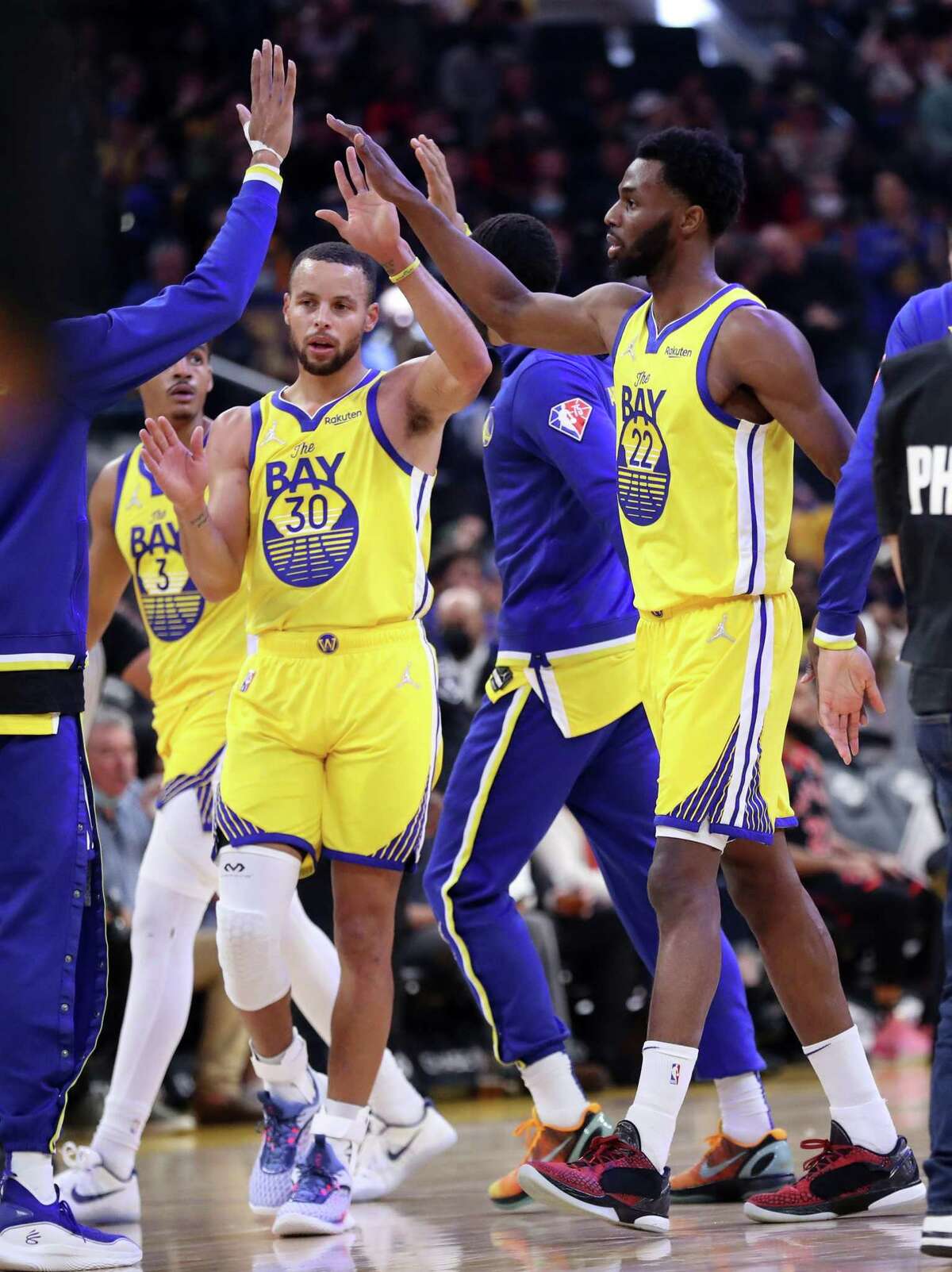 Golden State Warriors' Andrew Wiggins and Stephen Curry get high fives in 1st quarter against Toronto Raptors during NBA game at Chase Center in San Francisco, Calif., on Sunday, November 21, 2021.