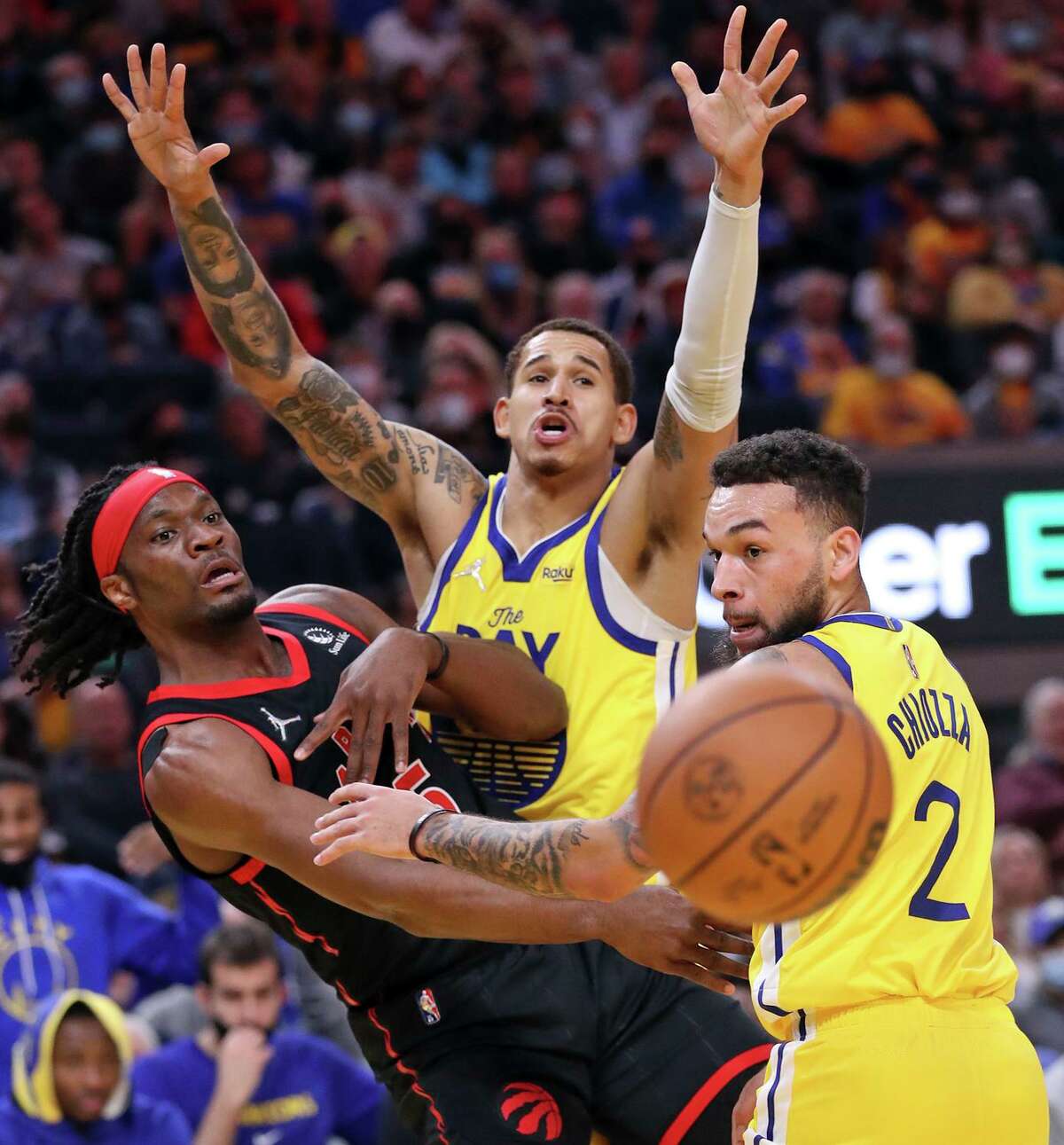 Toronto Raptors' Precious Achiuwa passes against defense of Golden State Warriors' Juan Toscano-Anderson and Chris Chiozza in 4th quarter during Warriors' 119-104 win in NBA game at Chase Center in San Francisco, Calif., on Sunday, November 21, 2021.