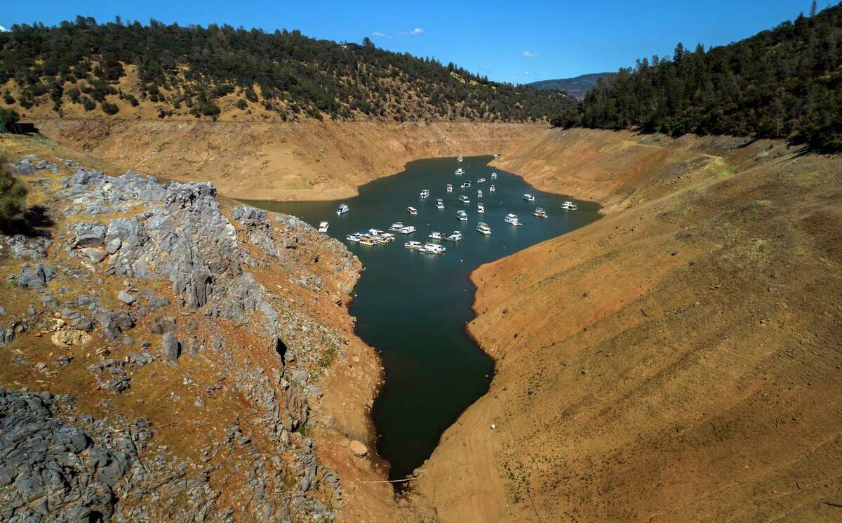 Houseboats float at a water level nearly 200 feet below average at Lime Saddle Marina at Lake Oroville in June of 2021. Low water levels at California reservoirs are forcing state officials to reduce how much water they expect to deliver this year.
