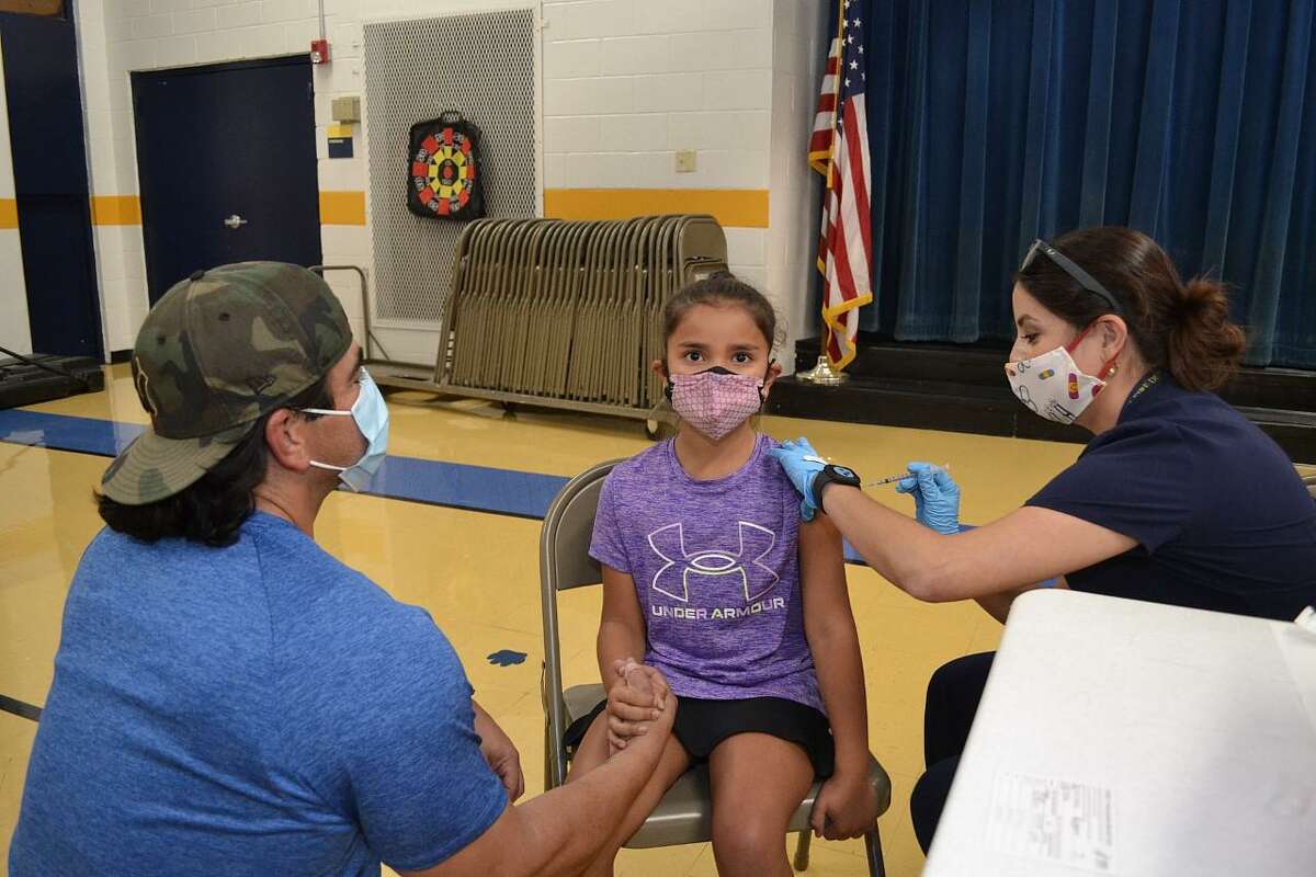 Clark Elementary Coach Robert De La Cruz tends to his daughter Kara as she received her Covid-19 vaccination from Jessica Mendiola R.N.