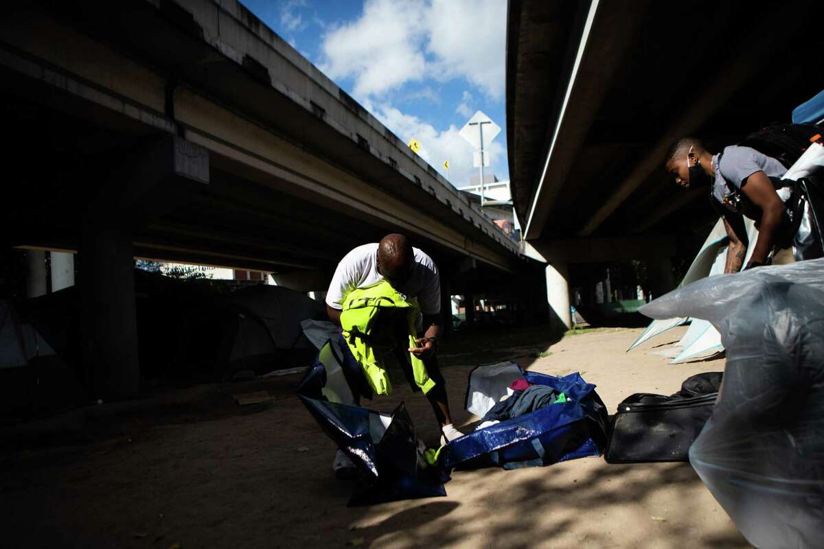 A man gathers his belongings from an encampment under I-45 before getting transported to new housing.