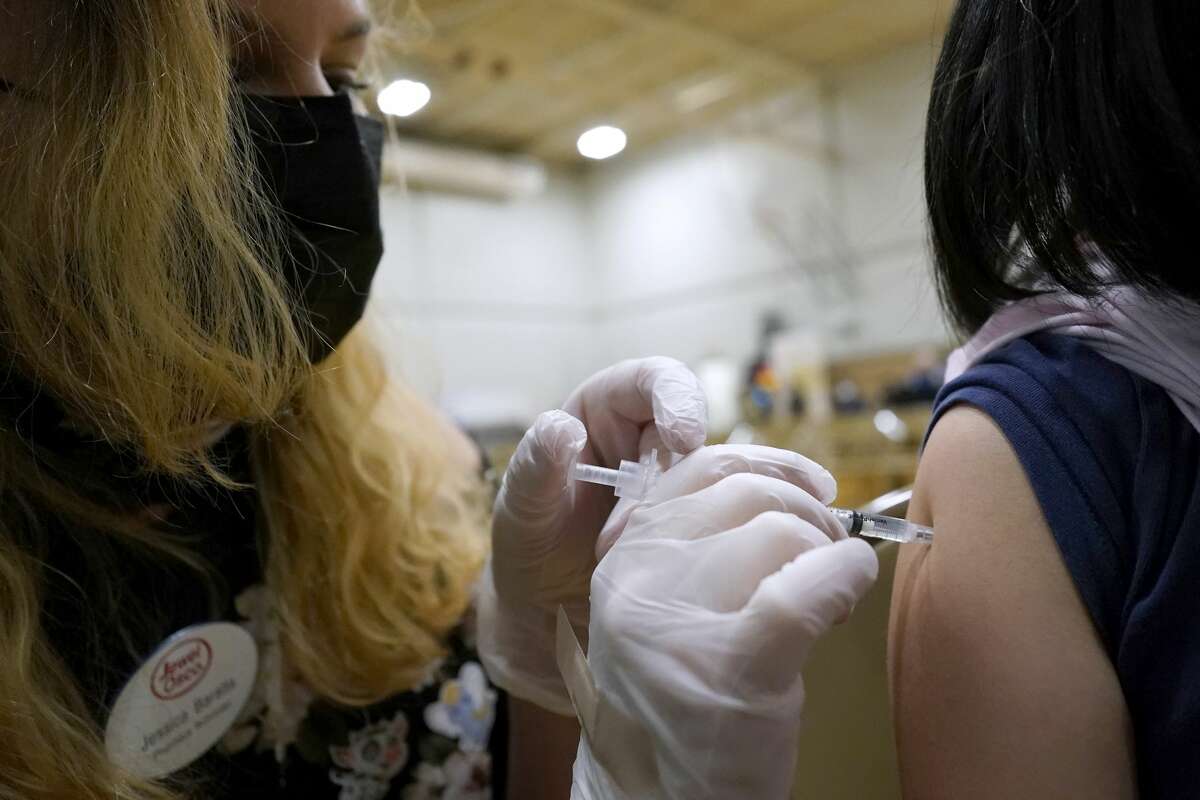 A health care worker administrates a dose of the COVID-19 vaccine to a student during a vaccination clinic in Wheeling.