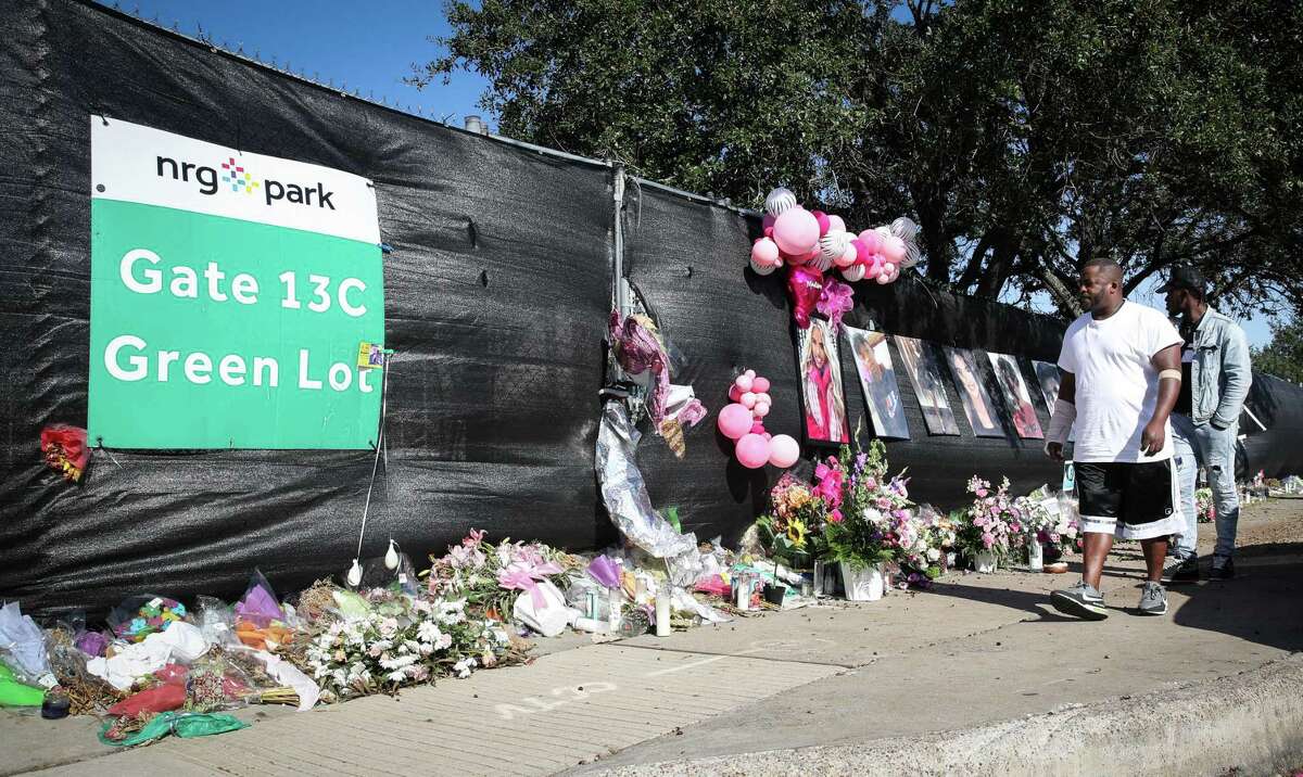 Samuel Bush, left, and his nephew Jackson Bush look at a memorial for victims of the Astroworld music festival before they speak with reporters Monday, Nov. 22, 2021, at NRG Park in Houston. The pair said they had worked as security guards at the festival, and they announced a lawsuit in response to the tragedy.