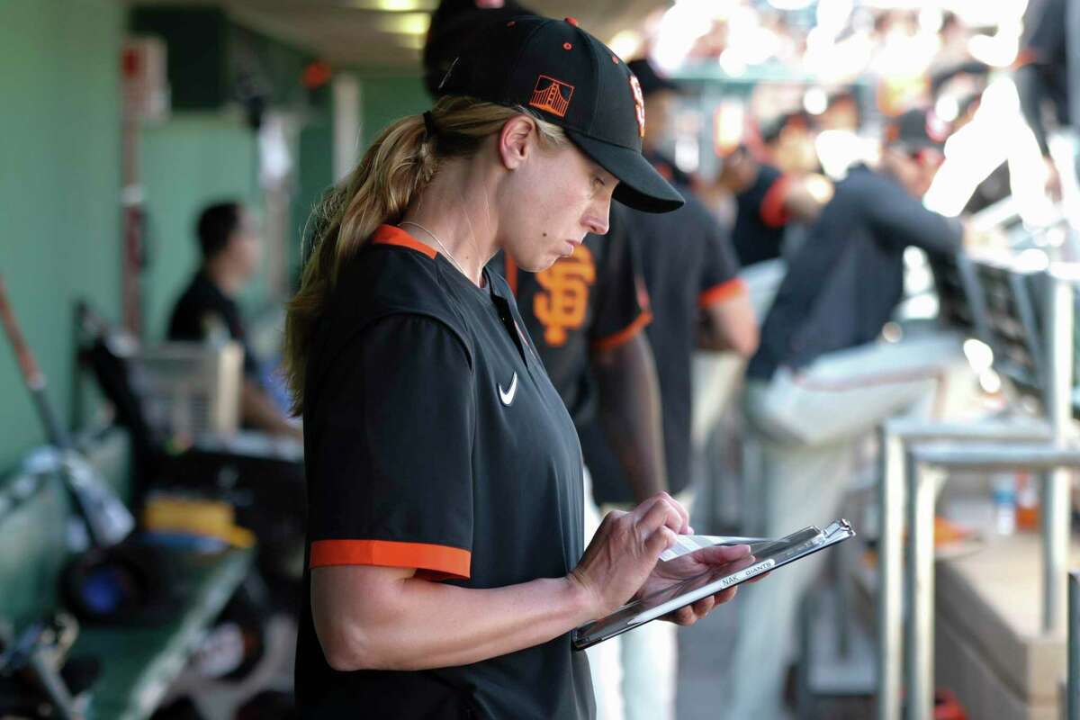 San Francisco Giants' coach Alyssa Nakken look over notes in the dugout before their spring training game against the Cleveland Indians at Scottsdale Stadium Thursday, March 5, 2020, in Scottsdale, Arizona.