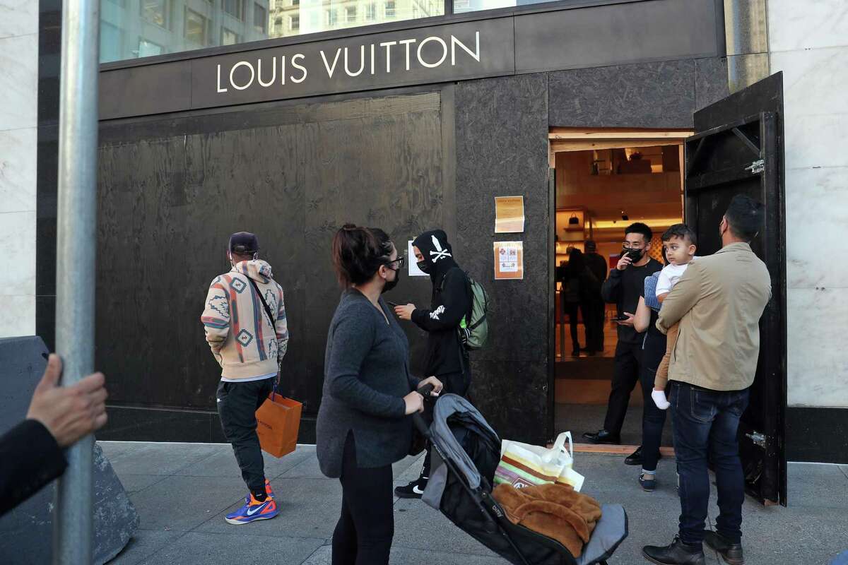 Customers wait to enter the Louis Vuitton store on Geary Street on Monday after a rash of break-ins last weekend.