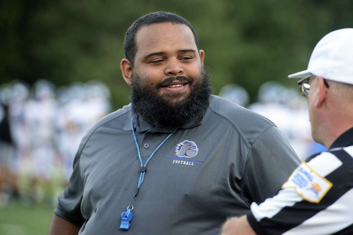 Bunnell High School head football coach Ty Jenkins meets with a referee prior to a game at Pomperaug High School, in Southbury, Conn. Sept. 17, 2021.
