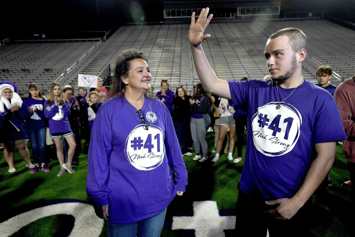 Mother Kim Borne looks on as Port Neches -Groves JV football player Noah Jackson waves to the crowd during a spirited community welcome home after being hospitalized in Houston 40 days with a traumatic brain injury suffered in a game last month. Photo made Monday, November 22, 2021 Kim Brent/The Enterprise