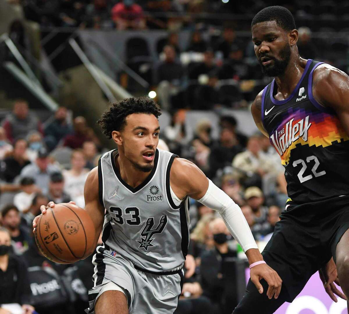 Tre Jones (33) of San Antonio Spurs drives by Deandre Ayton of the Phoenix Suns during second-half NBA action in the AT&T Center on Monday, Nov. 22, 2021.