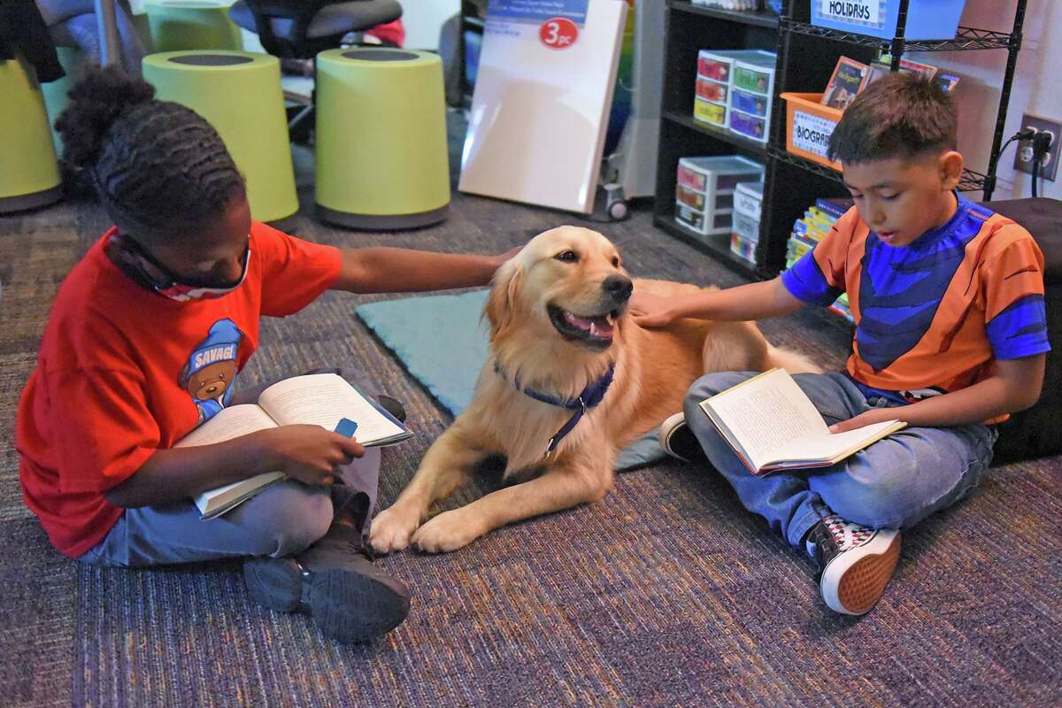 Walker Elementary School third grade students Shane Rogers, left, and Nathan Espinoza, right, read to Skye, the first full-time campus comfort dog in Texas on Oct. 21. Comfort dogs like Skye help assist school administrators, counselors, teachers and other staff members to foster a safe and effective environment for students to succeed academically, socially and emotionally.