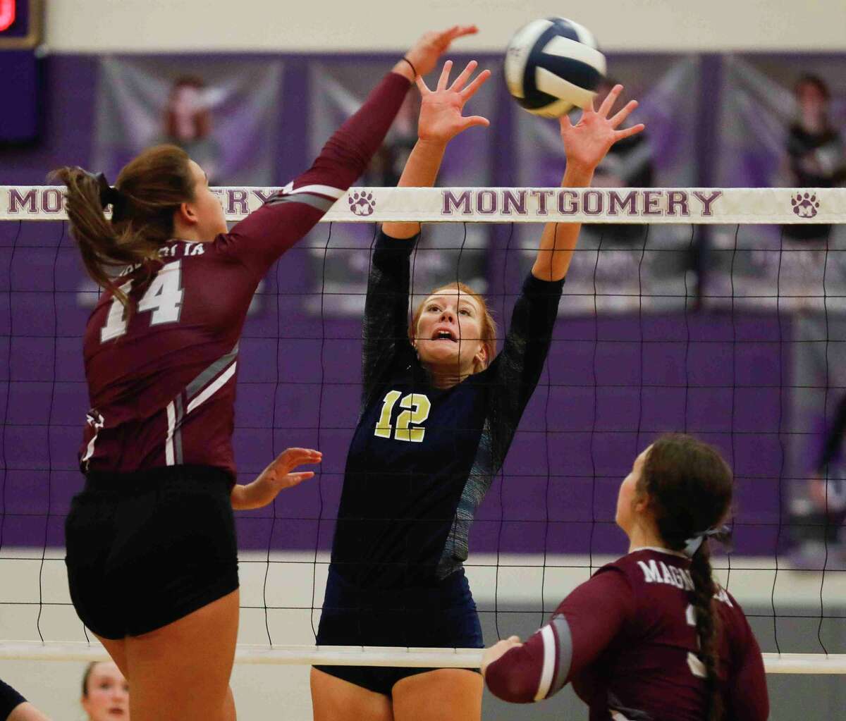 Magnolia middle blocker Alex Bull (14) gets a shot past Lake Creek middle blocker Grace Ellis (12) in the first set of a Region III-5A bi-district volleyball playoff match at Montgomery High School, Tuesday, Nov. 2, 2021, in Montgomery.