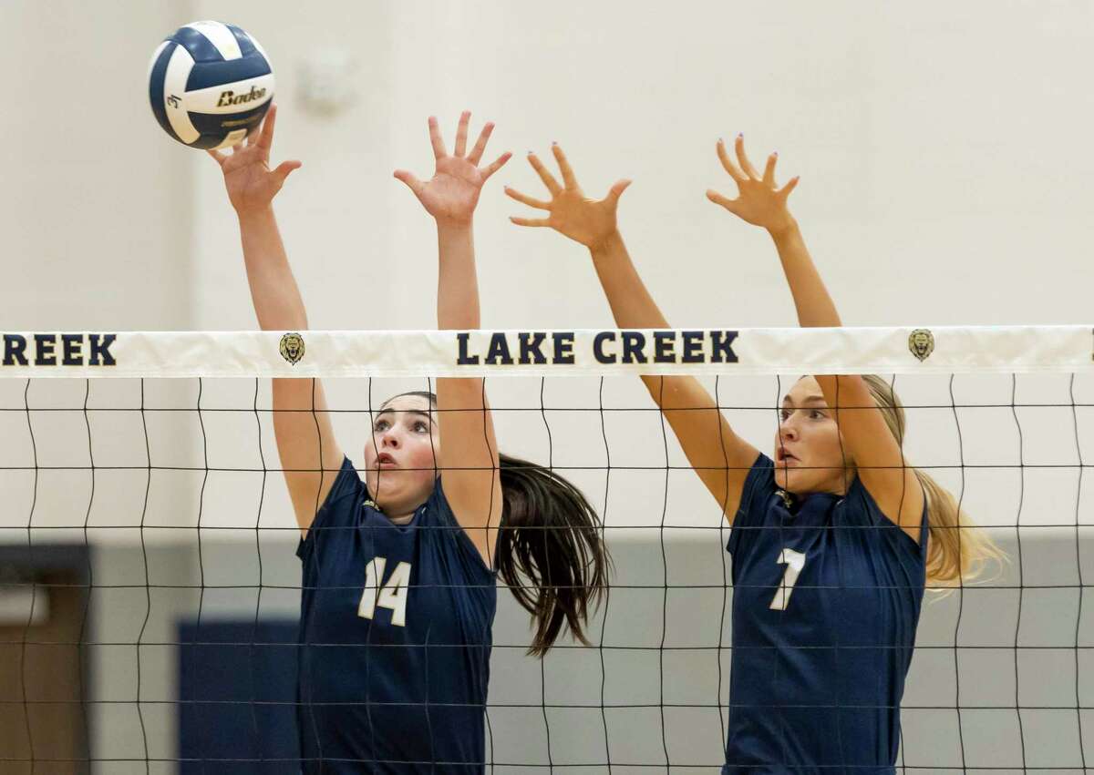 Kinzie Riley of Lake Creek (14) and Lauren Hilty (7) block the ball during the first set of a District 20-5A match against Cleveland at Lake Creek High School, Tuesday, Sept. 28, 2021, in Montgomery.
