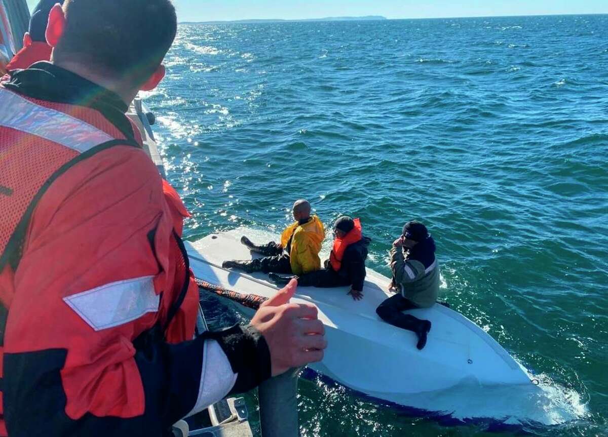 Coast Guard personnel rescue three fishermen from their capsized boat Monday off Tomales Bay.