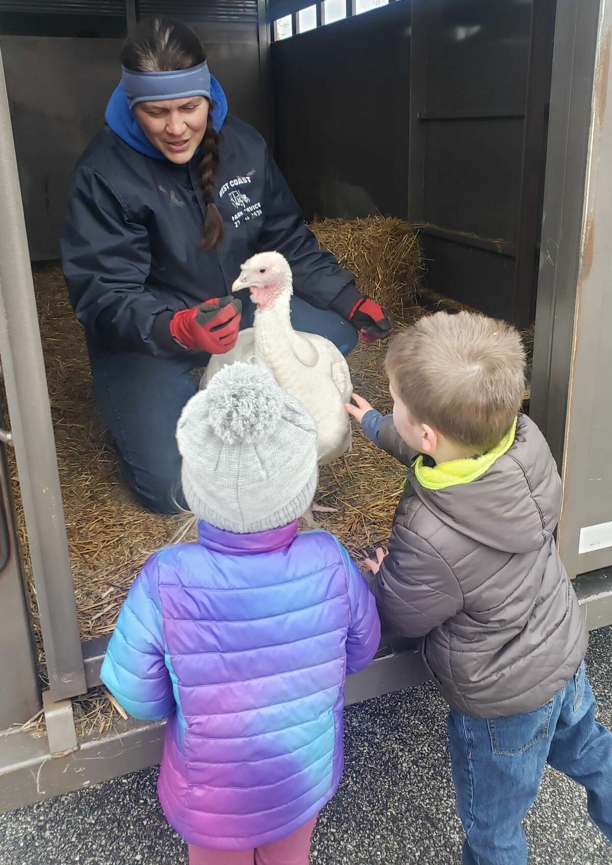 Elaine Bossingham, owner of Country View Farms in Manistee, lets Trinity Lutheran School students pet a turkey on Thursday.