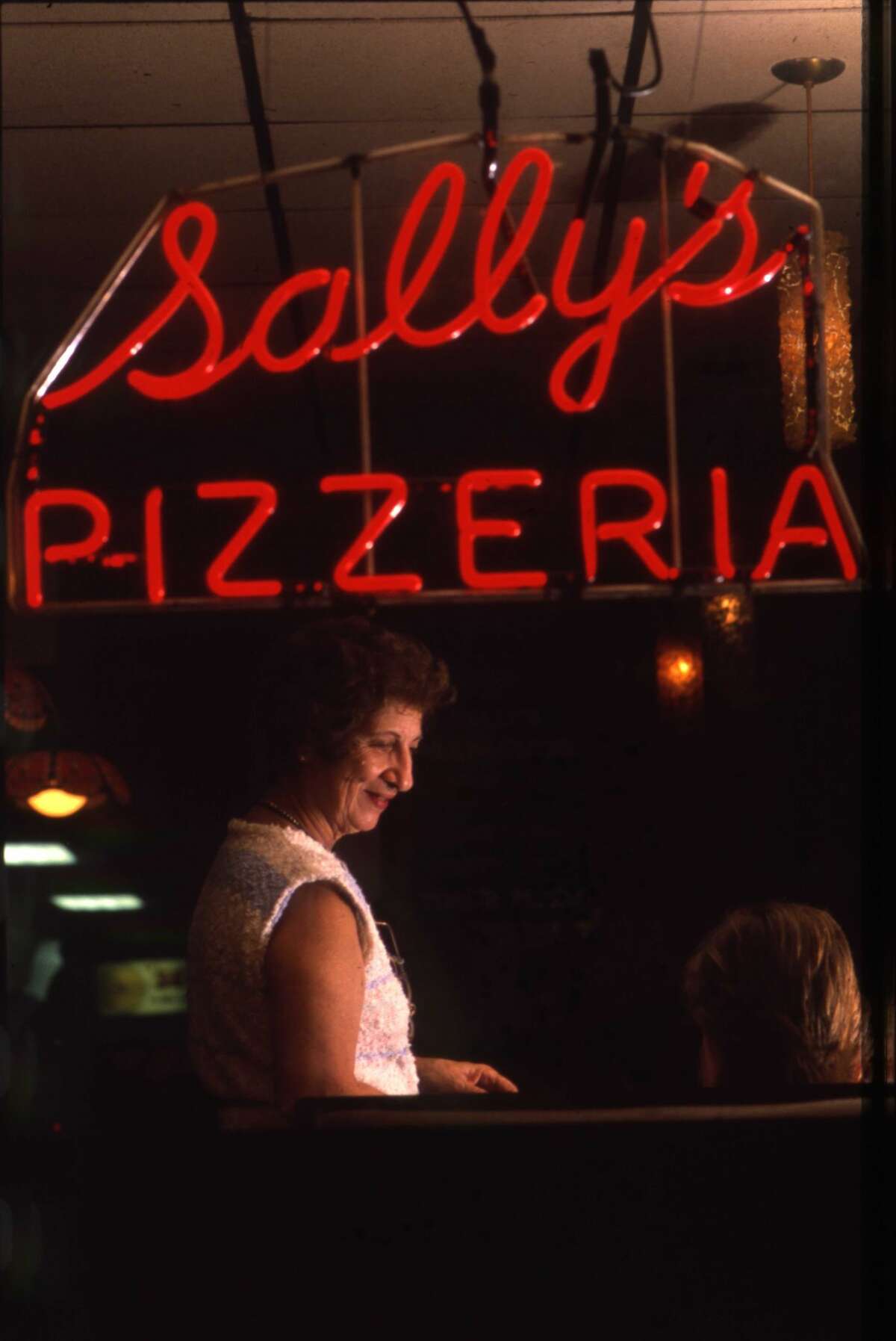 Flo Consiglio is pictured through the window of Sally's Apizza on Wooster Street in New Haven, Conn. The photo was originally taken by Arnold Gold on June 4, 1988. 